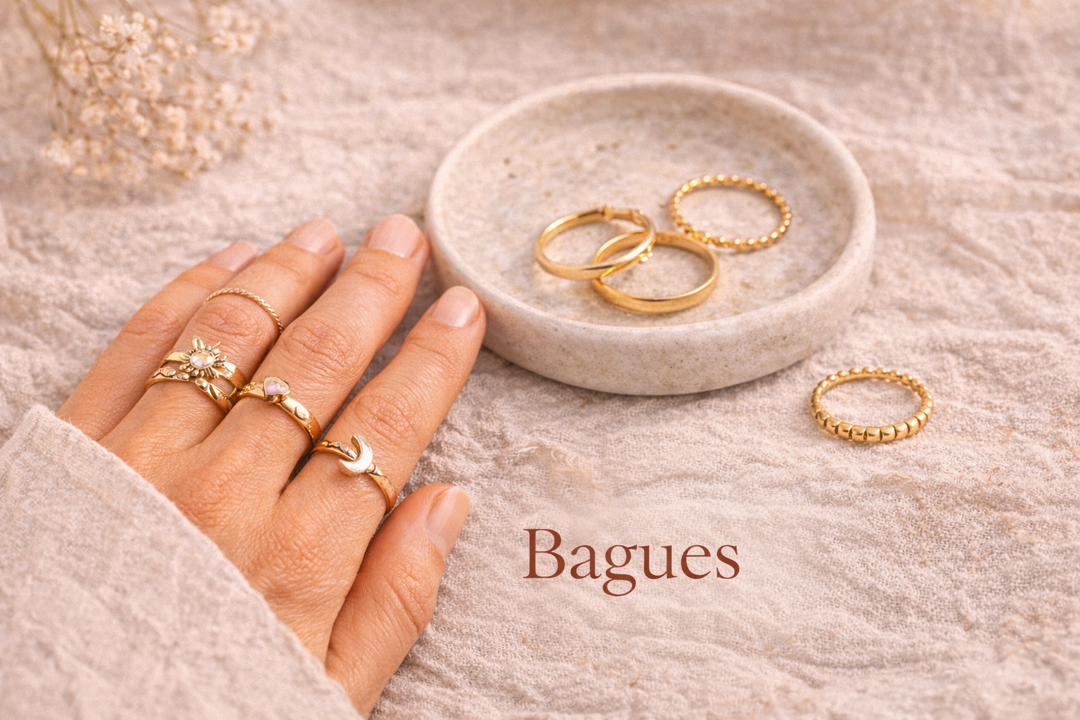 Main de femme portant des bagues bohèmes dorées sur fond beige, avec anneaux en acier inoxydable.