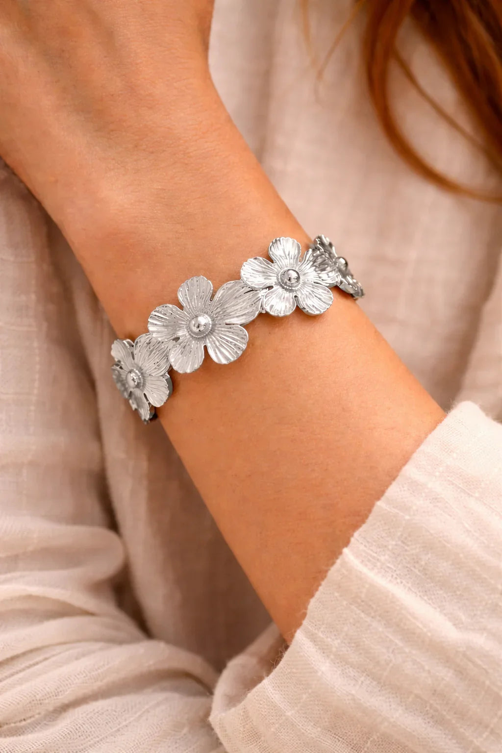 Bracelet femme acier inoxydable motif fleurs argenté porté au poignet, style bohème.