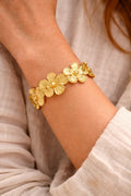 Bracelet doré femme en acier inoxydable avec fleurs bohèmes porté au poignet