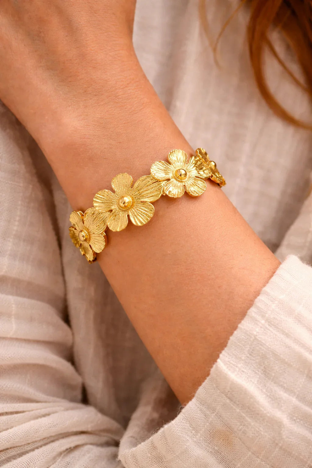 Bracelet doré femme en acier inoxydable avec fleurs bohèmes porté au poignet