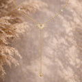 Collier bohème doré motif soleil en acier inoxydable, décoré de zircons, sur fond naturel.
